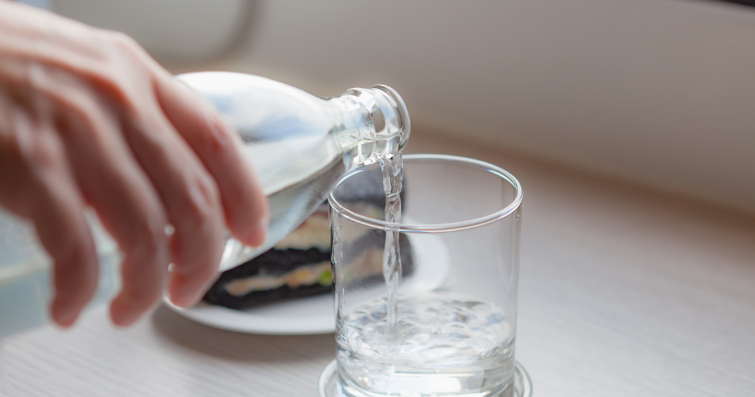 Pouring glass of water from a glass bottle