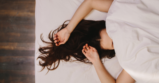 Woman lies in bed under covers sleeping